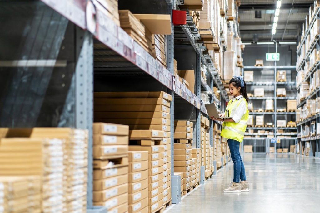 Engineer woman check stock details on tablet for checking boxes with logistics in warehouse