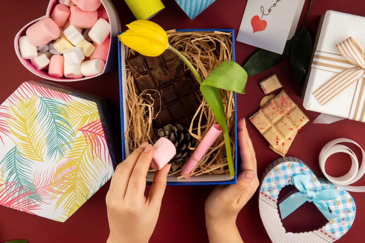 Top view of female hand putting marshmallow into a present box